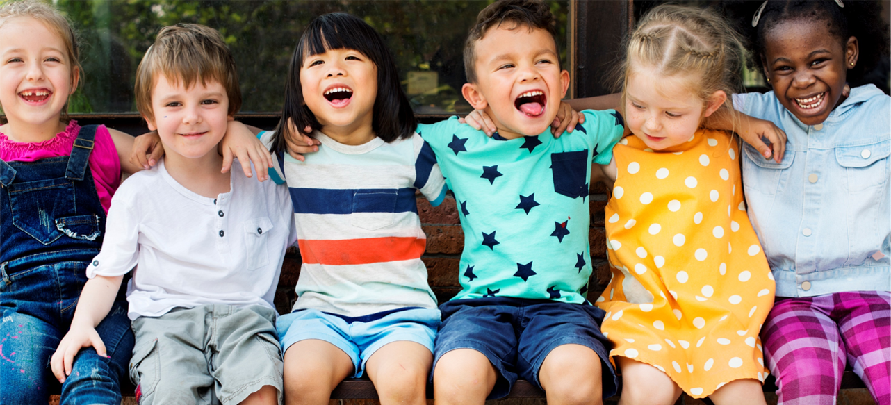 Kinder lachen und liegen sich in den Armen